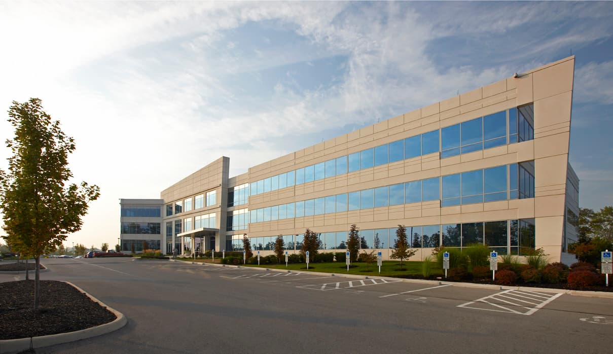 A full view of a precast concrete building with tan panels and lots of windows.