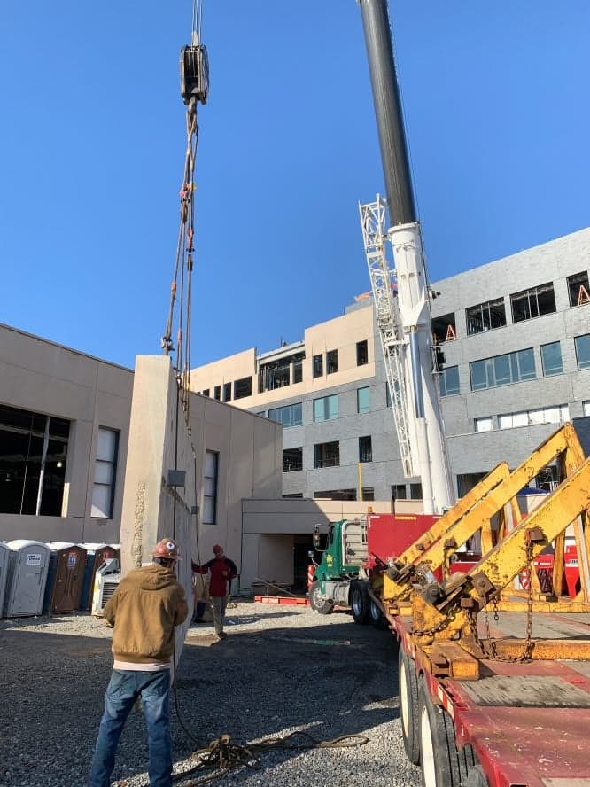 A crane on a construction site installing a precast concrete wall panel.