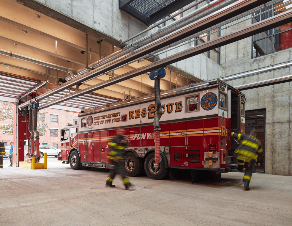 a fire truck and two firemen in the station.